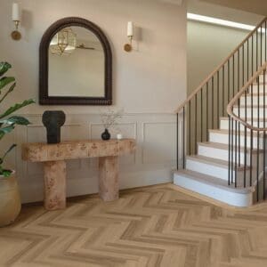 Belluno ash herringbone flooring installed in elegant entryway with staircase