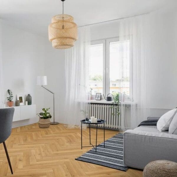 Modern living room with natural oak herringbone flooring featuring grey sofa and woven pendant light