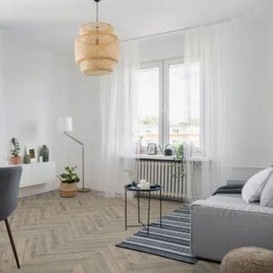 Modern living room with volcanic oak herringbone flooring featuring grey sofa and woven pendant light