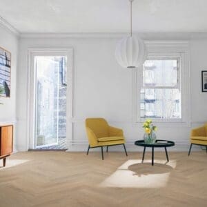 Bright living room with yellow accent chairs and desert oak herringbone laminate flooring