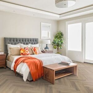 Modern bedroom with greige oak herringbone laminate flooring and wooden furniture