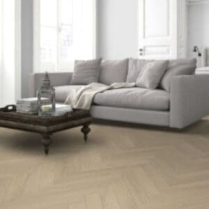 Light oak herringbone laminate flooring in modern living room with grey sofa