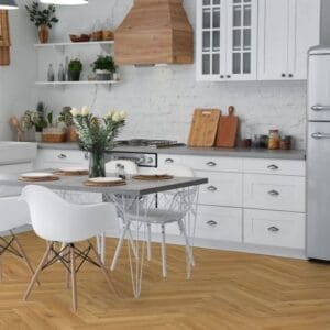 White kitchen with oak herringbone flooring and dining area with white chairs