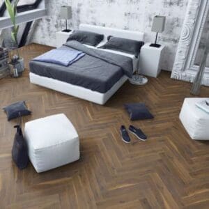 Contemporary bedroom with coffee oak herringbone laminate flooring and white furniture