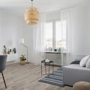 Volcanic oak laminate flooring installed in bright modern living room with grey sofa