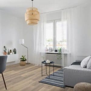 Greige oak laminate flooring in bright living room with grey sofa and woven pendant light