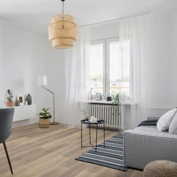 Greige oak laminate flooring in bright living room with grey sofa and woven pendant light