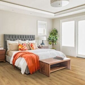 Natural oak laminate flooring in modern bedroom with grey headboard and orange accents