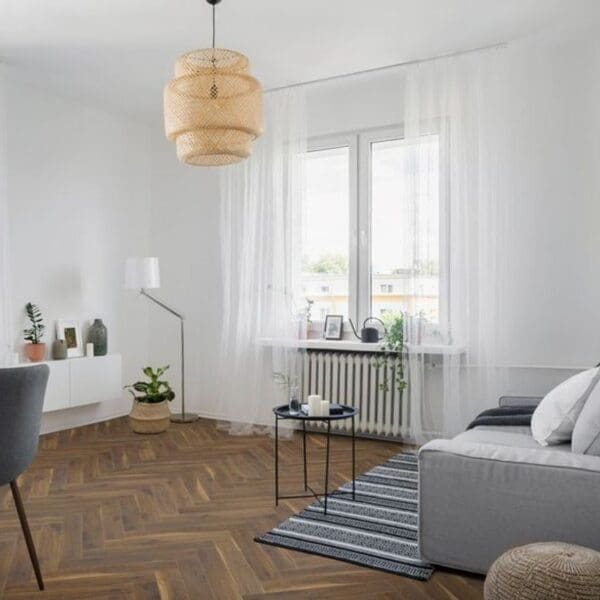 Modern living room with coffee oak herringbone laminate flooring and grey furniture