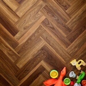 Overhead view of textures warm walnut herringbone flooring with children's toys
