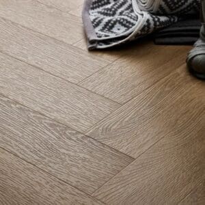 Textures light oak herringbone flooring with patterned rug and shoes
