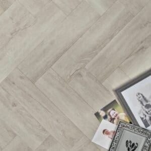 Elements Inspirations White Ash Herringbone EIH11 flooring with family photos and picture frames.