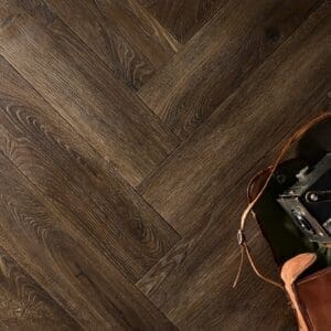 Textures LVT Tudor Oak Herringbone TH03 flooring in a herringbone pattern with a vintage camera.