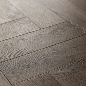 Close up of Textures LVT Tudor Oak Herringbone TH03 luxury vinyl flooring showing wood grain detail.