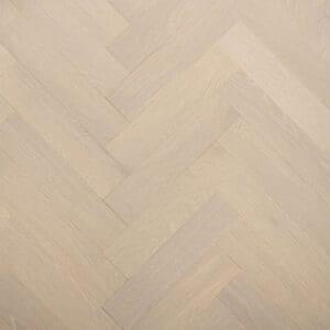 A top down view of grey brushed lacquered oak herringbone engineered wood flooring showing the parquet pattern.