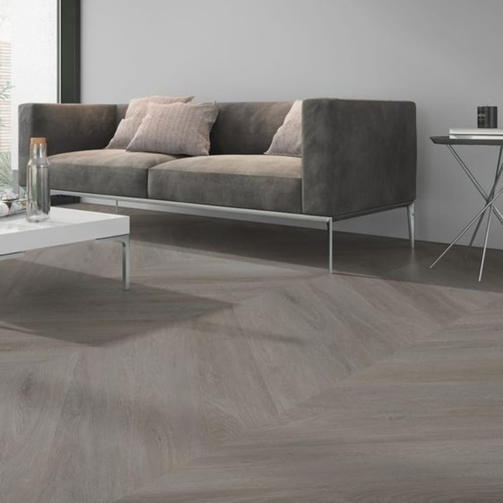 Detailed view of English Oak Taupe Chevron flooring installed in a lounge area next to a grey sofa