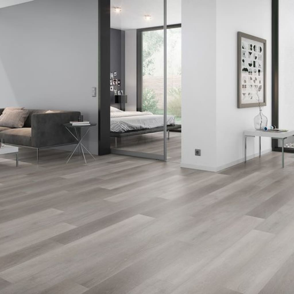 Modern bedroom interior featuring Flemish Oak Grey flooring with a grey sofa and white walls.