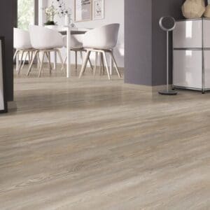 Close up of Prestige Oak Natural vinyl flooring in a bright dining room with white chairs.