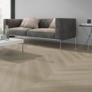 Detailed view of raw oak light natural chevron flooring in a lounge setting with a grey sofa