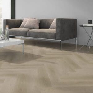 Raw Oak Light Natural herringbone flooring installed in a modern living room with a grey sofa