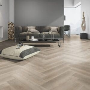 Modern living room featuring Soft Oak Greige Herringbone flooring with grey sofa and minimalist decor