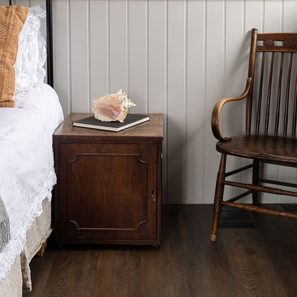 Harvey Maria Burnt Fig flooring installed in a bedroom with a wooden side table and chair