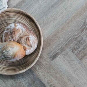 Dormouse herringbone flooring installed in a kitchen with a blue island and wooden stool