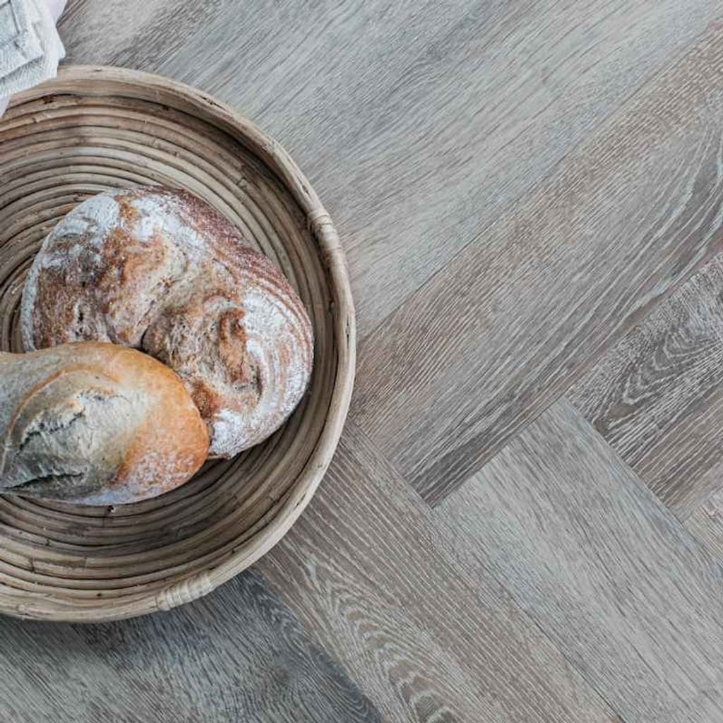 Dormouse herringbone flooring installed in a kitchen with a blue island and wooden stool