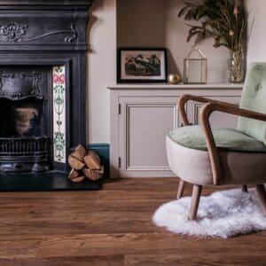 Lifestyle shot of Harvey Maria English Oak Plank in a living room featuring a fireplace and armchair