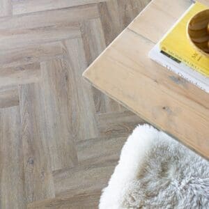 A tabby cat sitting on Flaxen Oak Herringbone parquet flooring in a modern room