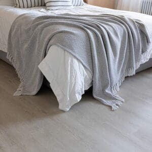 Wide shot of Pale Oak Plank flooring in a modern bedroom with wood panelled walls