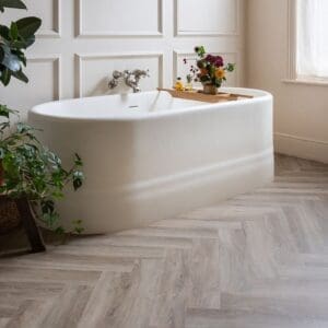 Harvey Maria Oast Herringbone flooring in a modern bathroom with a freestanding white bathtub