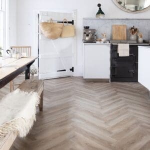 Close up of Oast Herringbone vinyl flooring next to a rustic wooden dining table and bench