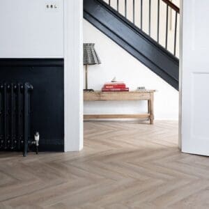 Wide room shot of Rosehip Herringbone flooring in a modern home with black stairs