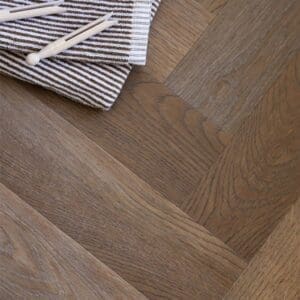 Rye Herringbone wood effect flooring in a utility room with white cabinetry and brass handles