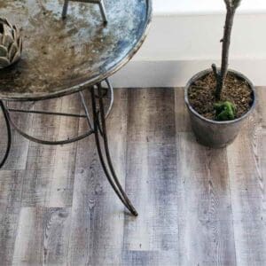 Detailed view of Weathered Plank flooring under a rustic metal table and plant pot