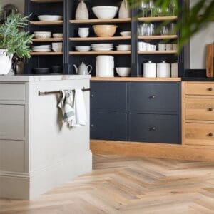 Close up of Wicker Herringbone LVT flooring showing wood grain detail next to a wooden stool