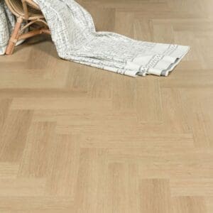 Austrian Larch flooring in a room setting with a wicker chair and throw