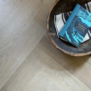 Close up view of Pale Rattan Herringbone planks showing wood grain texture and ashy tones.