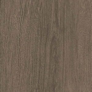 Smoked Oak luxury vinyl flooring installed in a room with a dark teal wall and blue cushion