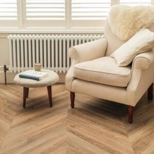 Modern interior with Toasted Oak Chevron flooring and a cream armchair by a radiator.