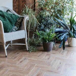 Herringbone wood effect flooring in a room with many green plants