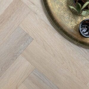 Overhead view of light oak parquet flooring with decorative brass tray